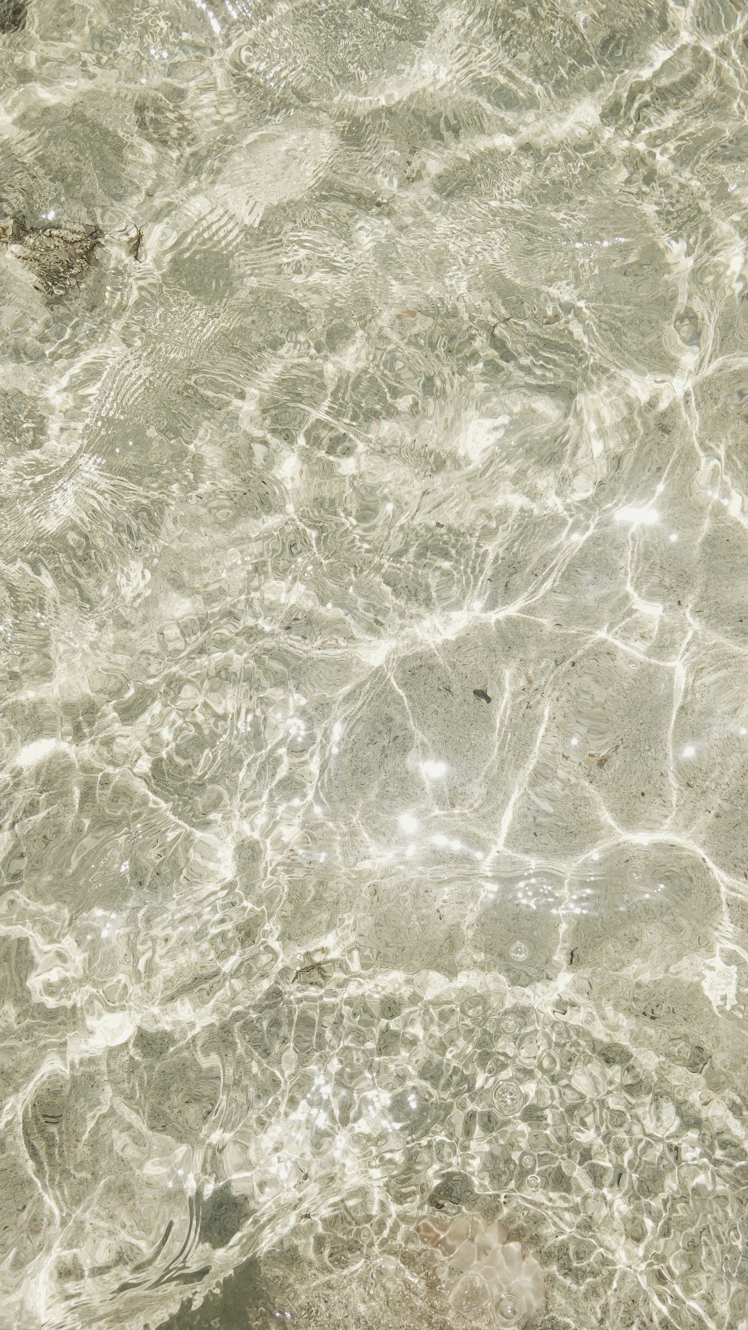 Sunlit ripples on clear shallow water over a sandy seabed
